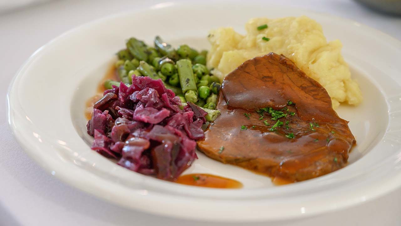 Beef, mashed potato, red cabbage, runner beans, and peas with gravy